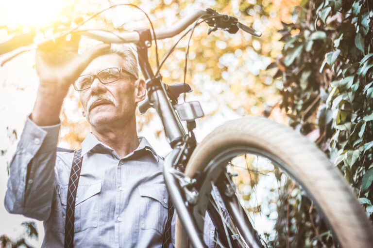 older man carrying bicycle