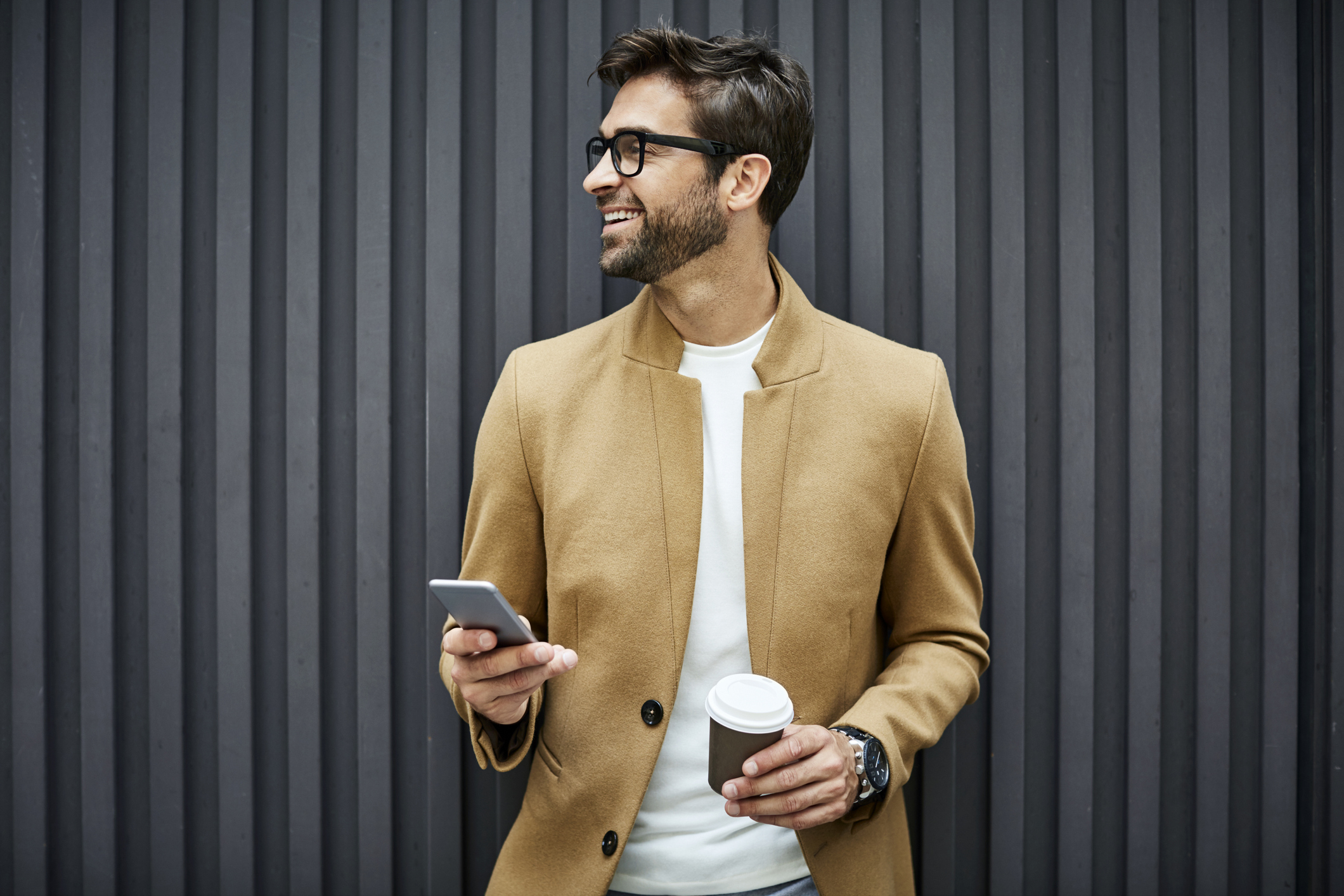 Smiling businessman with smartphone and cup